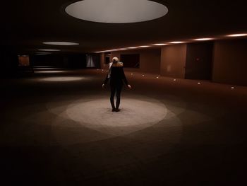 Full length of woman walking in illuminated corridor