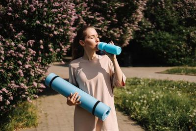 Woman holding a while standing against plants