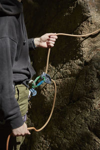 Mid section of rock climbers hands holding rope