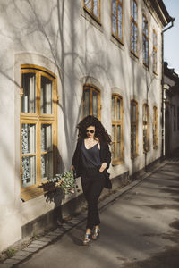 Full length of woman standing against building in city