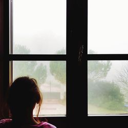 Rear view of woman looking through window