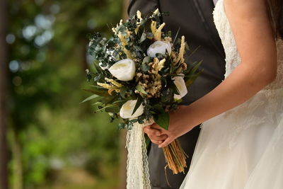 Low angle view of woman holding bouquet of flowering plant - wedding flowers 