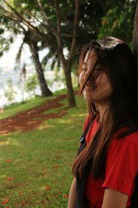 Side view of young woman against trees