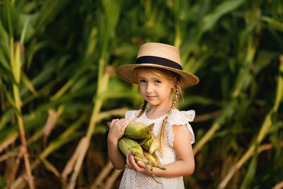 Portrait of cute girl holding corn standing outdoors