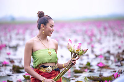 Woman holding pink flower in lake