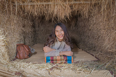 Portrait of young woman smiling while lying on mat in hut at village