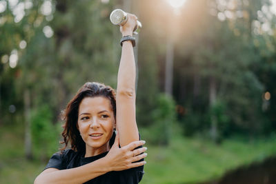 Smiling woman exercising while standing outdoors