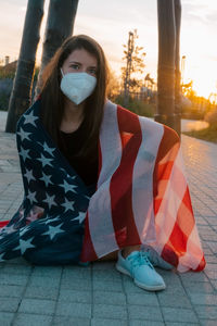 Portrait of young woman sitting on sidewalk in city