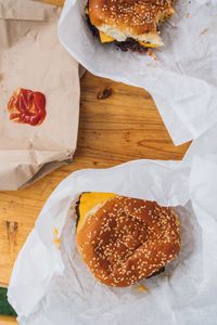 Two cheeseburgers with sesame buns with a side of french fries and ketchup