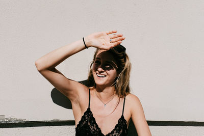 Portrait of smiling young woman standing against wall