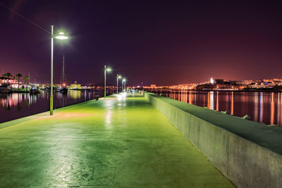 Illuminated bridge over river against sky at night