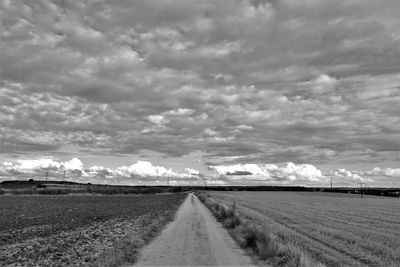 Road amidst field against sky