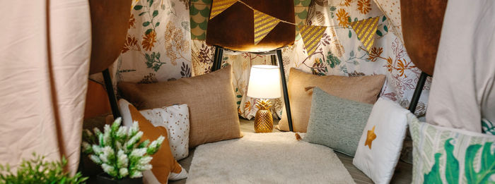 Interior of diy tent made with three chairs and bed sheets at home