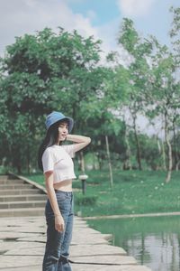 Smiling young woman looking away while standing by lake