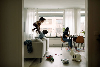 Side view of young woman using mobile phone at home