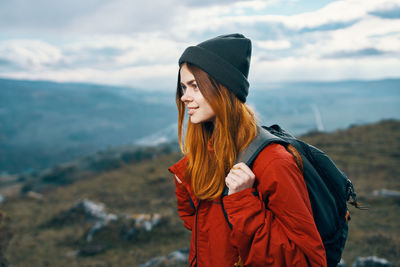 Woman wearing hat standing against mountain during winter