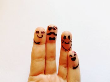 Close-up of hand holding toy against white background