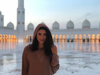 Portrait of beautiful young woman standing in city