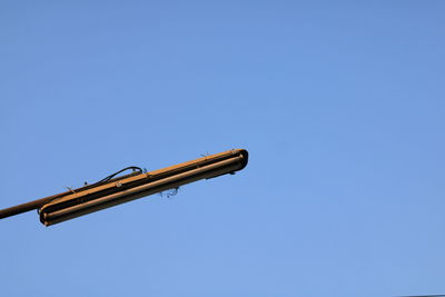 Low angle view of crane against clear blue sky