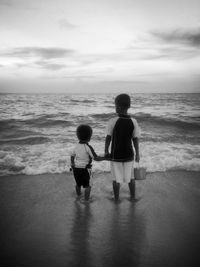 Rear view of children on beach against sky