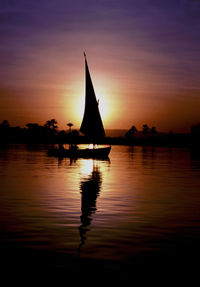 Silhouette sailboats in sea against sky during sunset