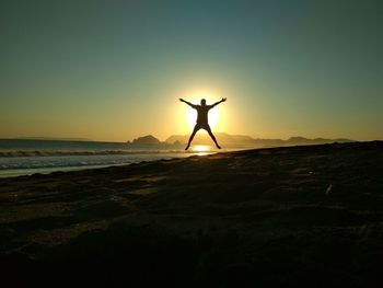 Silhouette man standing in water at sunset