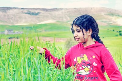 Teenage girl looking at plants while standing outdoors