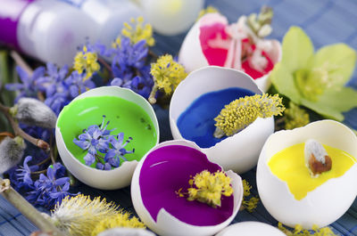 Close-up of eggshell with flowers and paint tubes on table