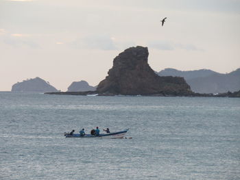 People on boat in sea against sky