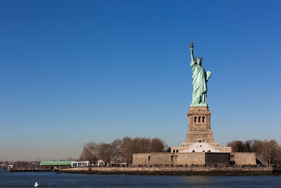 Statue in city against clear sky