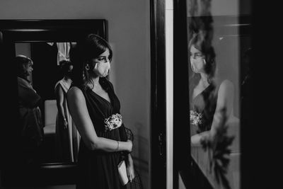 Bride wearing mask standing by mirror