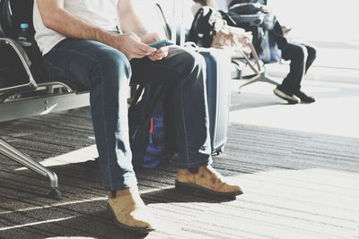 Low section of man using mobile phone while sitting on bench