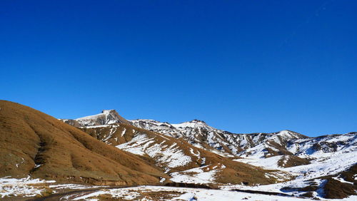 Scenic view of snowcapped mountains against clear blue sky