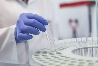 Cropped hand of scientist putting test tube in rack