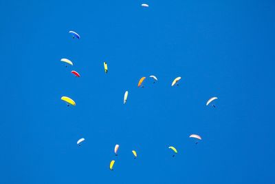 Low angle view of birds flying against blue sky