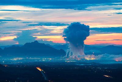 Smoke emitting from mountain against sky during sunset