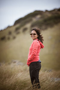 Young smiling woman standing on grassy hill