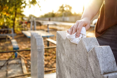 Midsection of person holding cross in cemetery