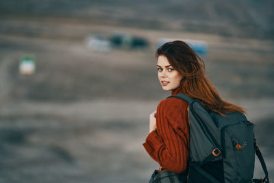 Young woman looking away while standing outdoors