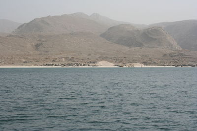 Scenic view of sea by mountain against sky