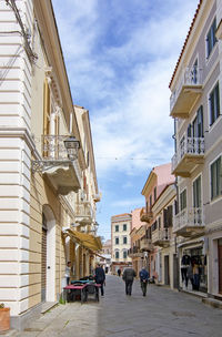 People on street amidst buildings in city against sky