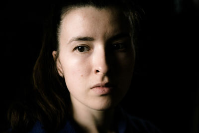 Close-up portrait of woman against black background