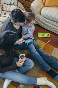 High angle view of father sitting on sofa