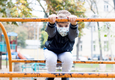 Happy kid playing on the playground and wearing face mask due to covid-19 pandemic.