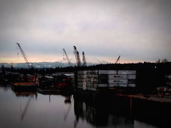 Cranes at harbor against sky