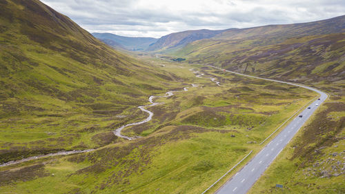 Scenic view of road by mountains against sky