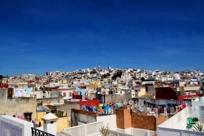 High angle view of houses by sea against blue sky