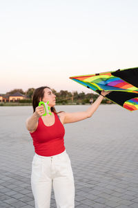 Full length of woman holding umbrella standing against sky