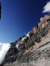 Low angle view of rocky mountains against blue sky