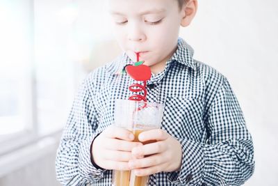 Close-up of boy drinking drink at home